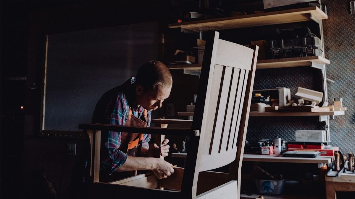 Craftsperson working on a wooden chair in a workshop